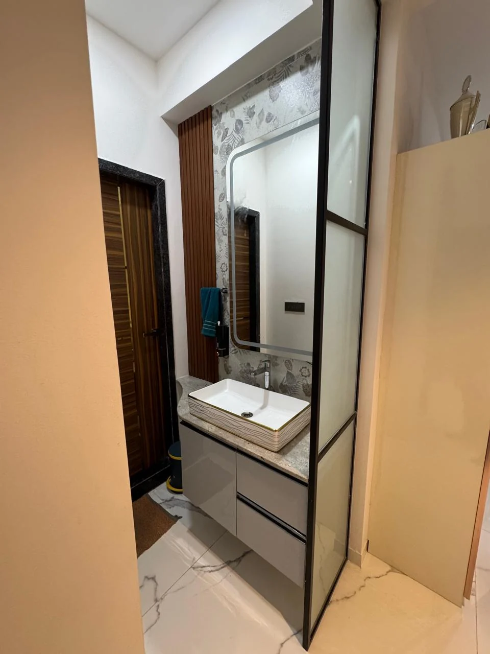 Bathroom vanity with a vessel basin, timber-fronted cabinet and a backlit mirror