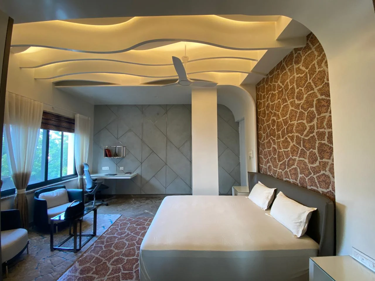 Bedroom with a curved cove ceiling above a stone feature wall and a study desk