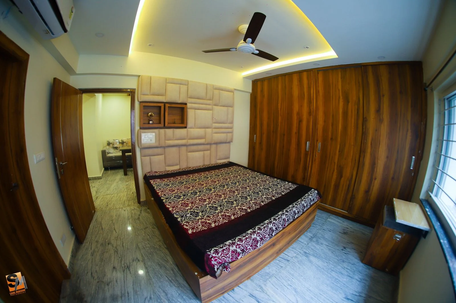 Bedroom with a curved cove ceiling above an upholstered headboard wall and timber wardrobes