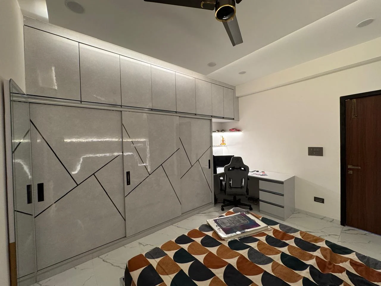 Bedroom with full-height wardrobes along the corridor wall and a study desk with a task chair