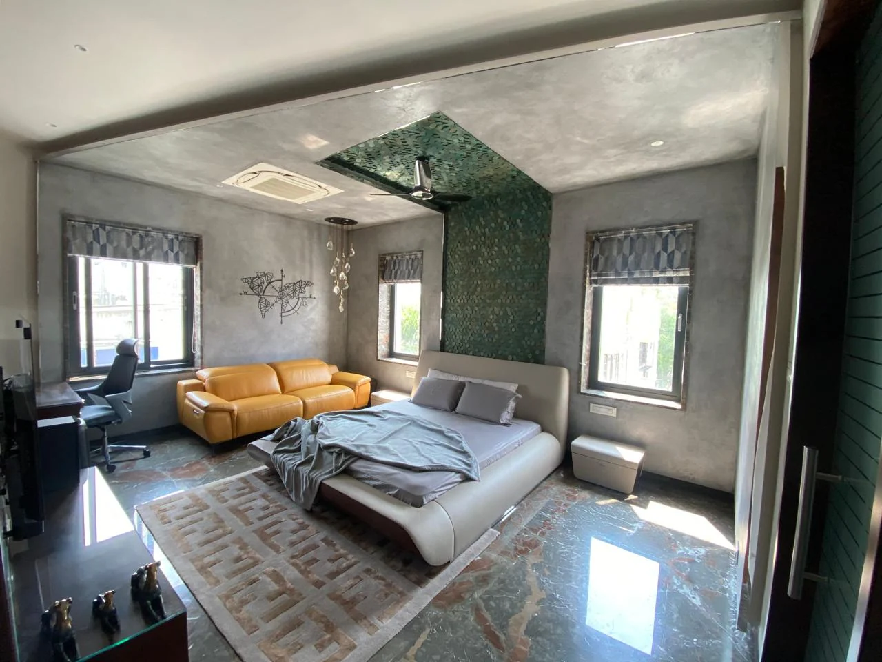 Bedroom with a green marble slab set into the ceiling above a tan leather sofa