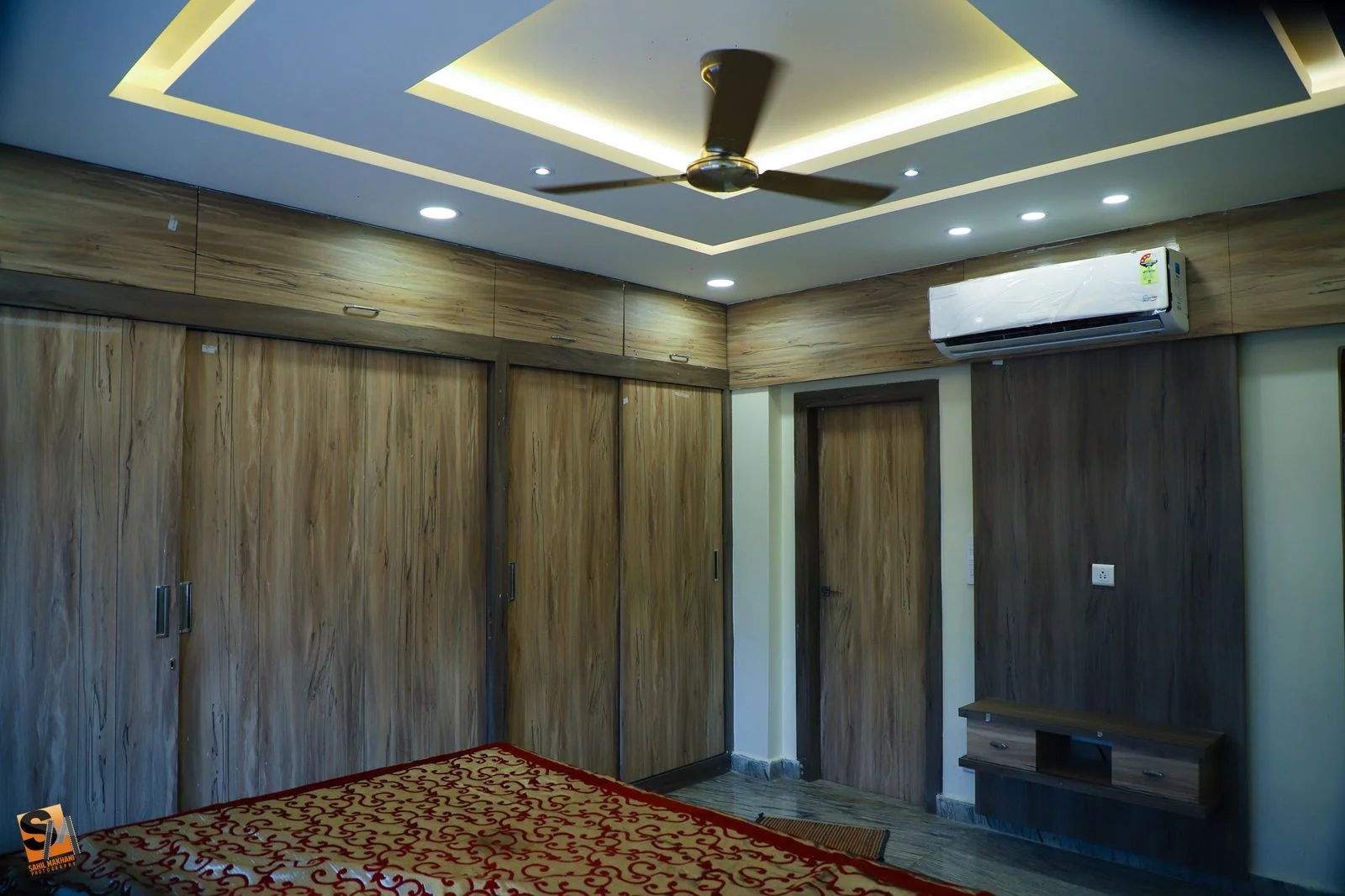 Bedroom with a grey-washed laminate wardrobe wall and wall-mounted television