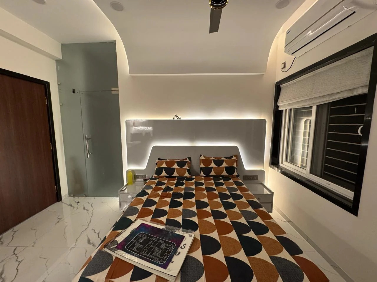 Corner view of a bedroom with a lit headboard recess