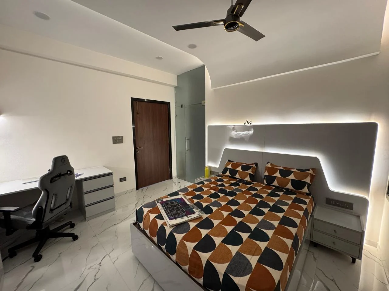 Bedroom with a lit headboard recess and a study desk on the daylight side