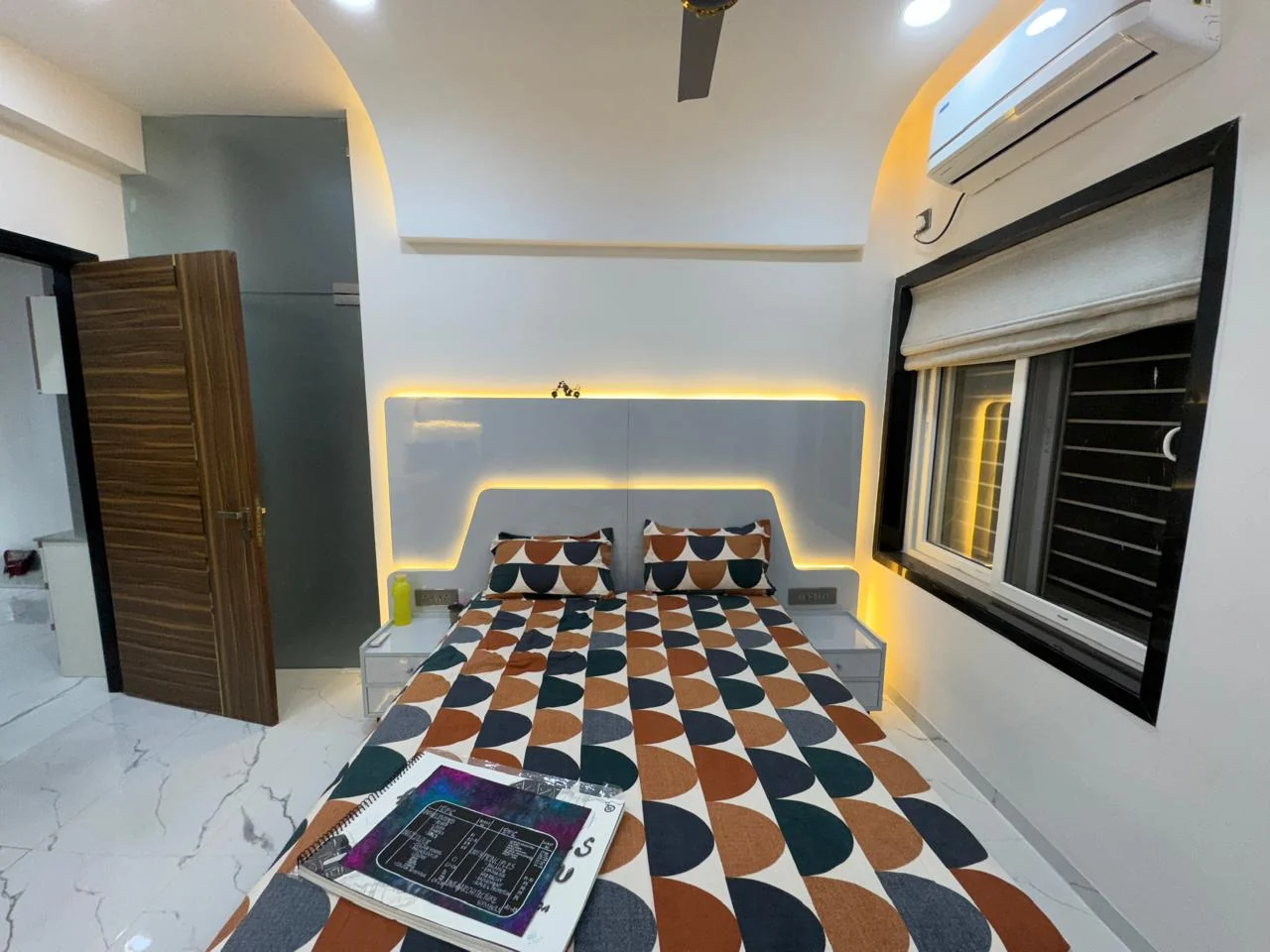 Bedroom with a lit headboard recess, seen from the window side