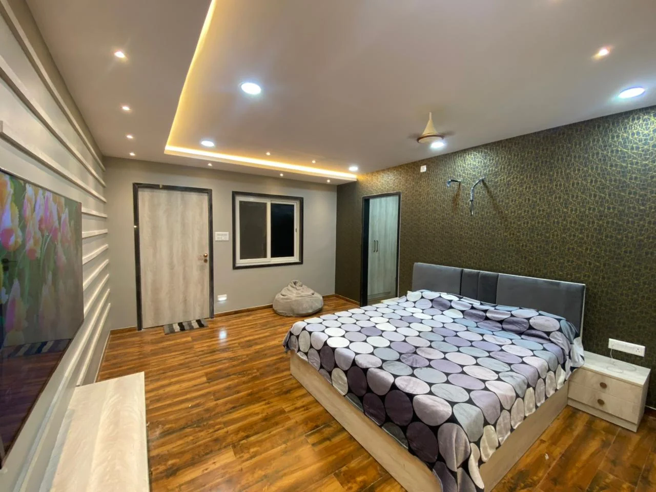 Bedroom with a deep green and gold textured feature wallpaper and slat panelling on the return wall
