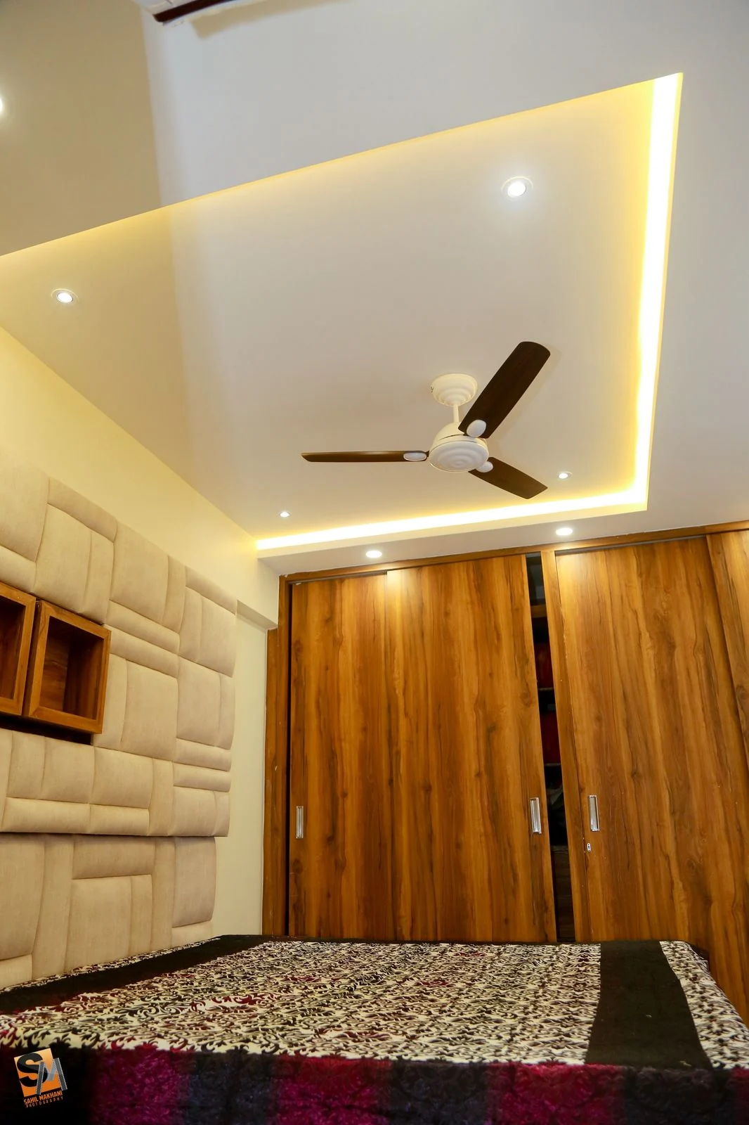 Corner view of an upholstered headboard beside timber wardrobes