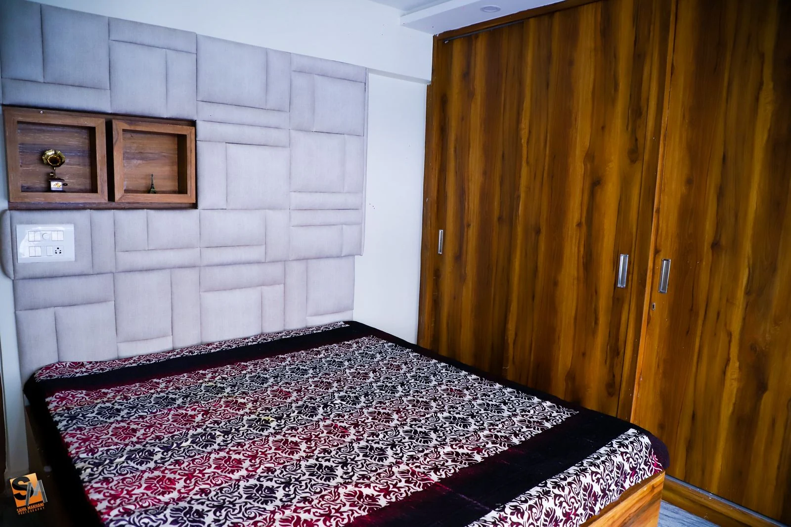 Wide view of a bedroom with an upholstered headboard wall and full-height timber wardrobes