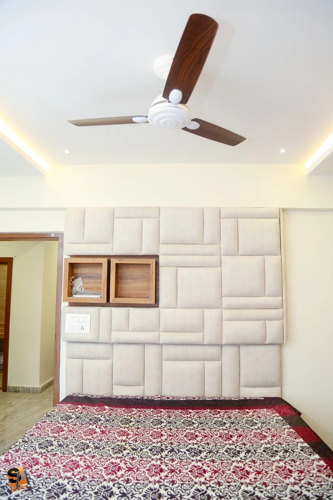Bedroom with an upholstered panel headboard wall and inset timber display niches