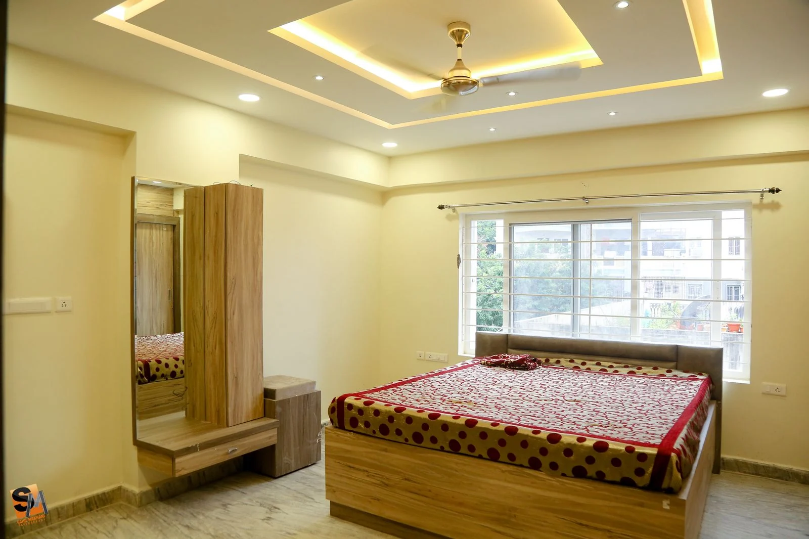 Bedroom wardrobe run with a dressing mirror beneath a cove-lit ceiling