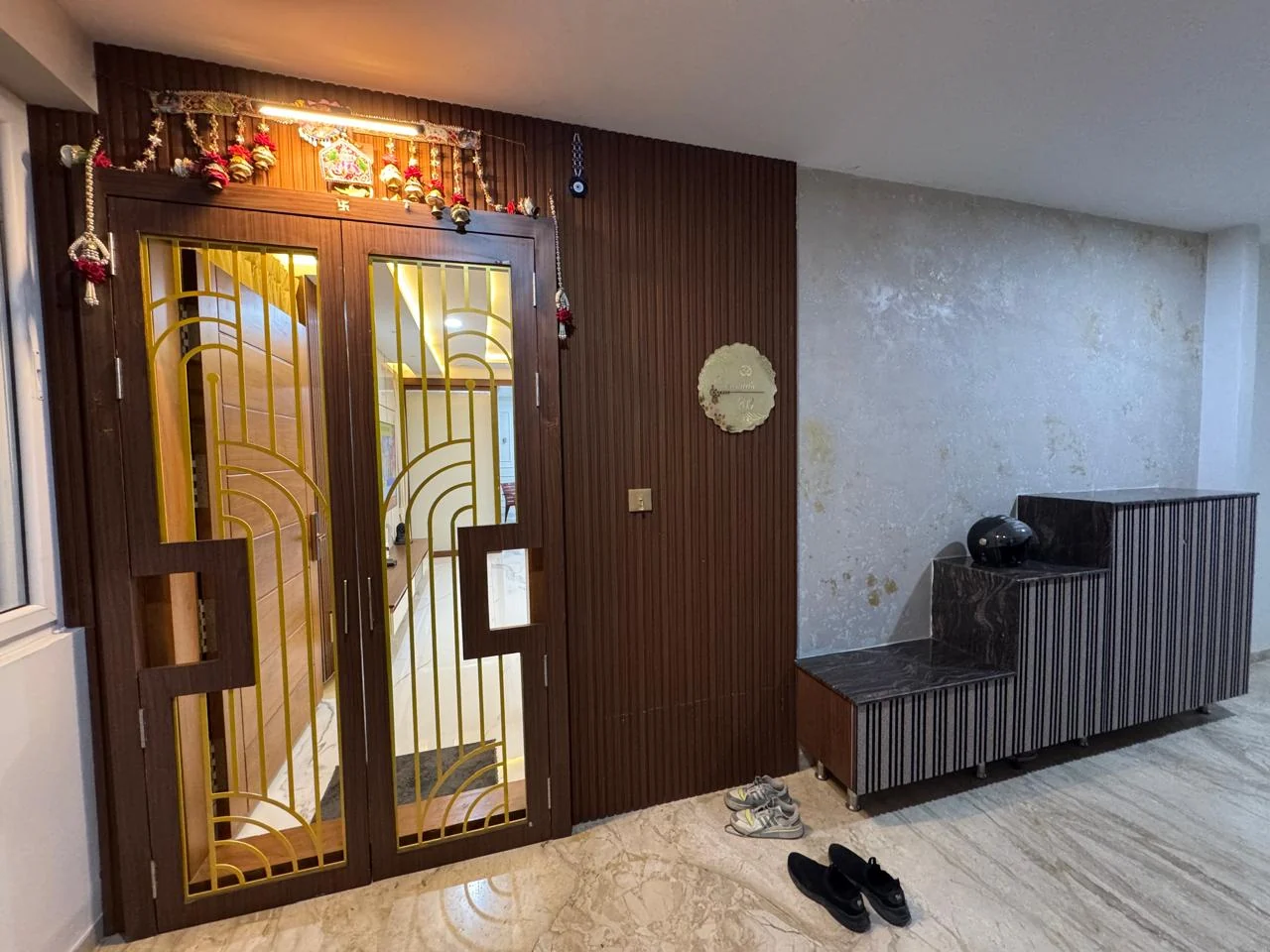 Entrance lobby with carved timber double doors inset with brass grille work against a marble wall