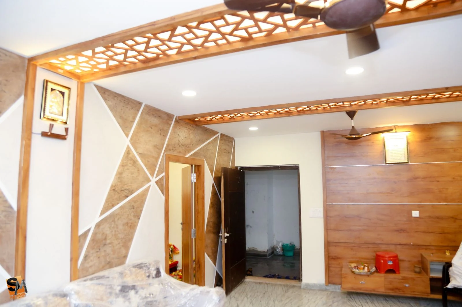 Hall feature wall in geometric stone-look panels beside a timber television unit