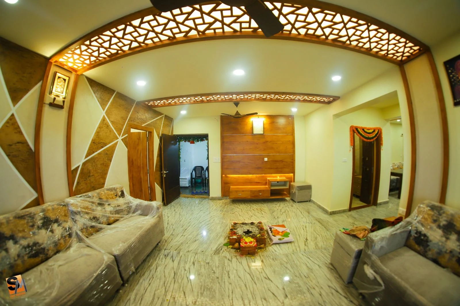 Completed living room beneath a curved CNC-cut fretwork ceiling arch, with a geometric stone and timber feature wall