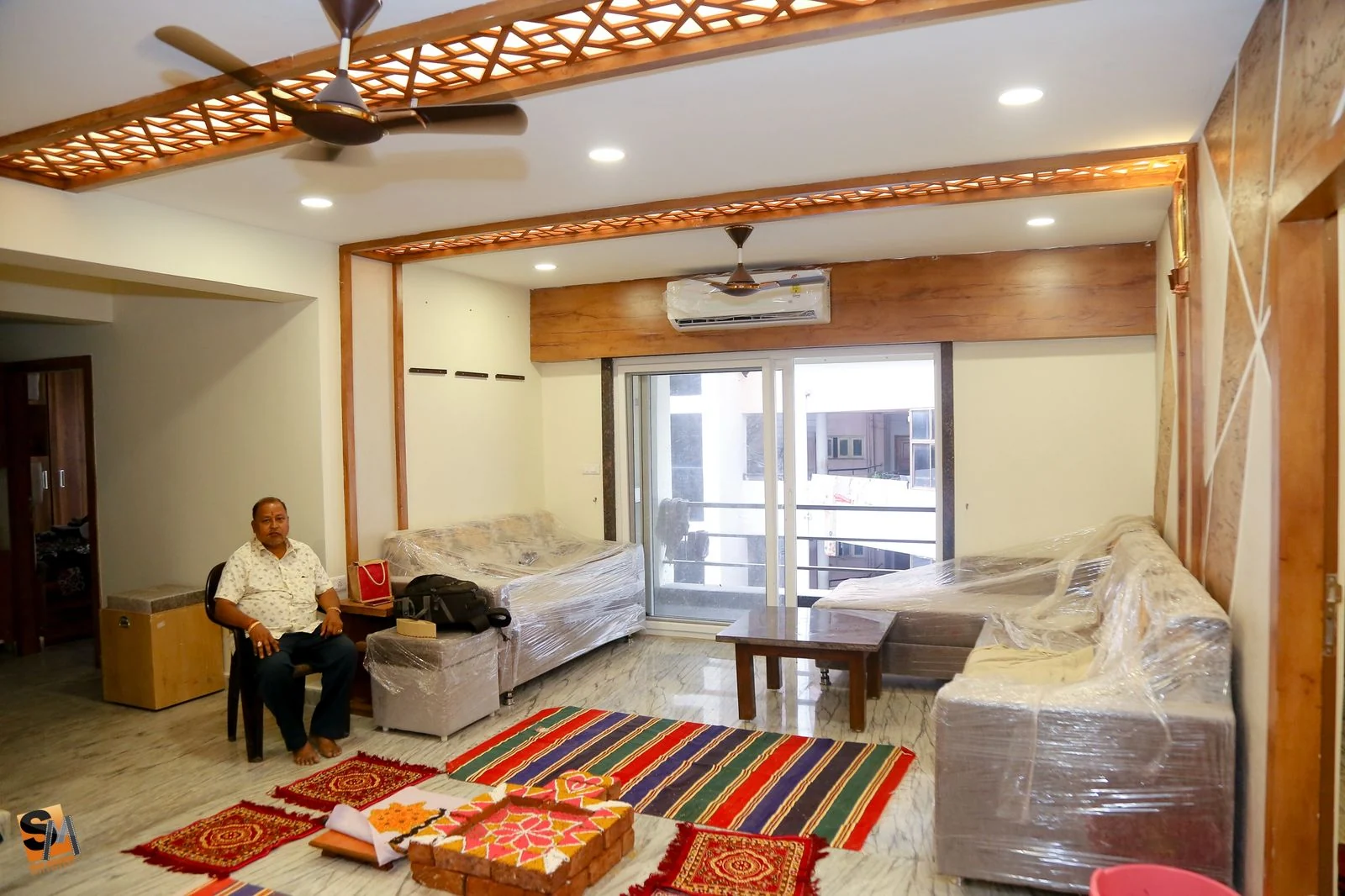 Living room seating beneath the fretwork ceiling with balcony doors beyond