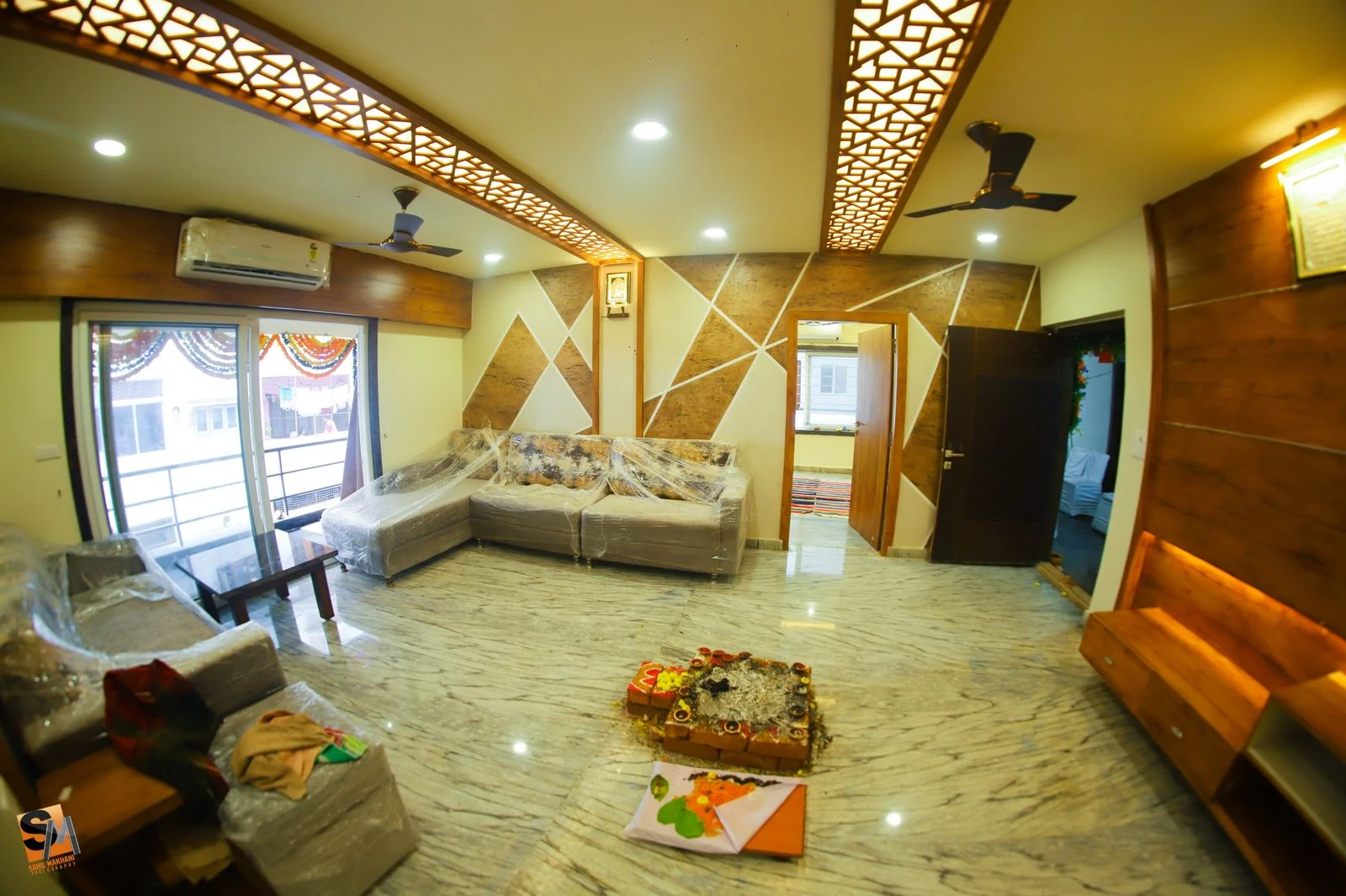 Living room with a sectional sofa beneath the fretwork ceiling, balcony doors beyond