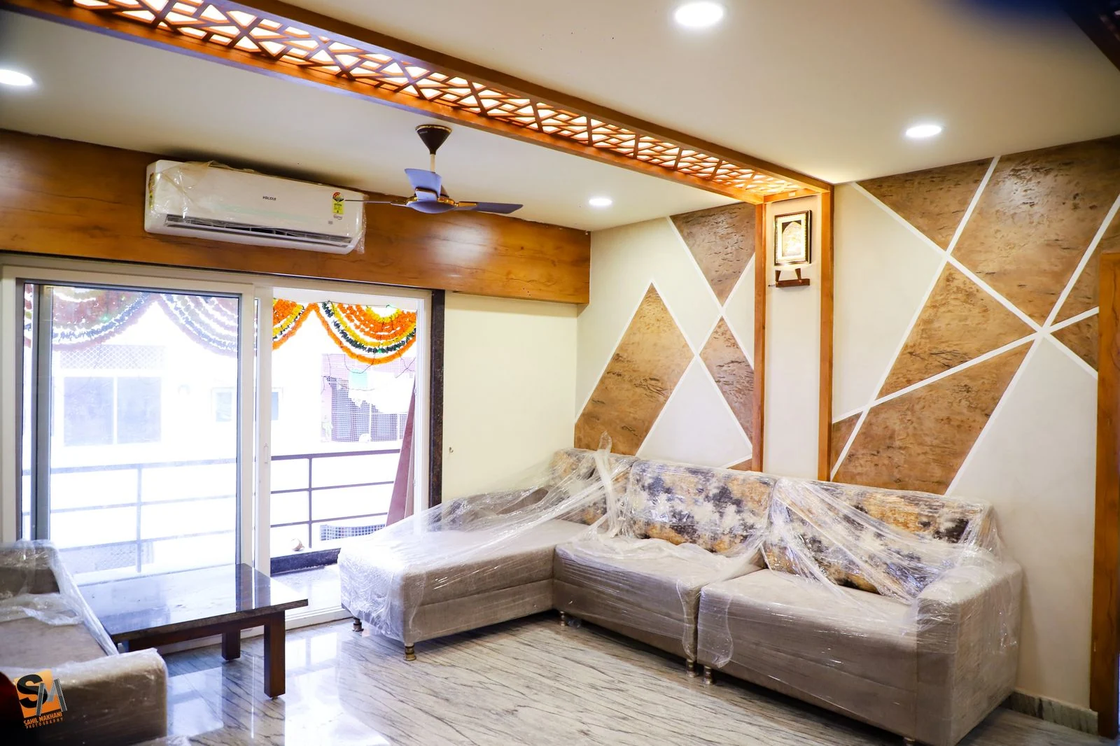 Living room with a fretwork ceiling band above a geometric stone and timber feature wall