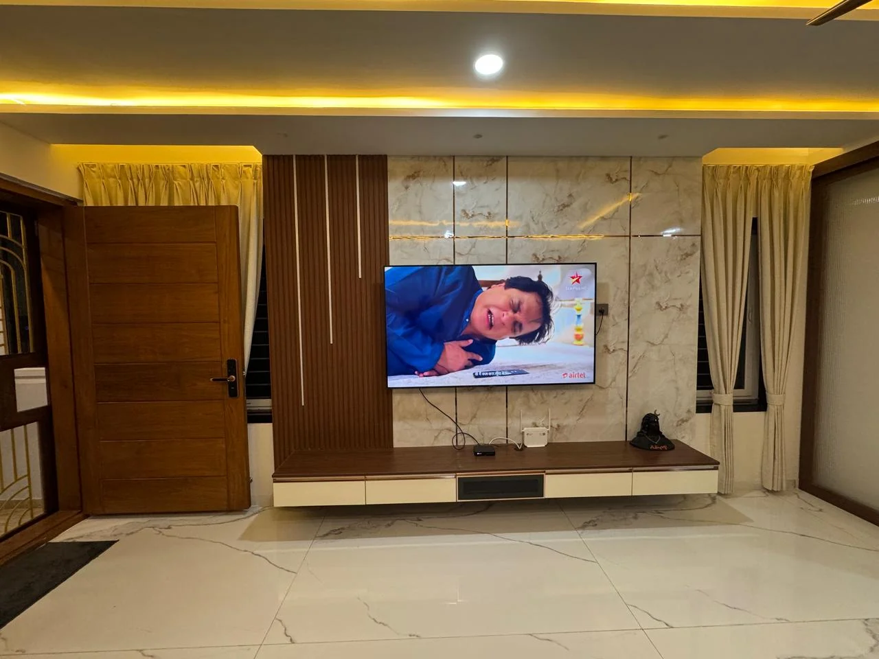Marble television wall with fluted timber panelling and concealed cove lighting
