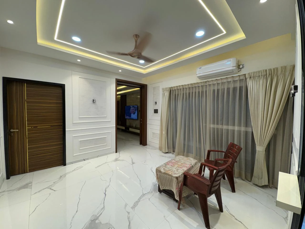 Living room with a recessed cove ceiling above large-format marble flooring