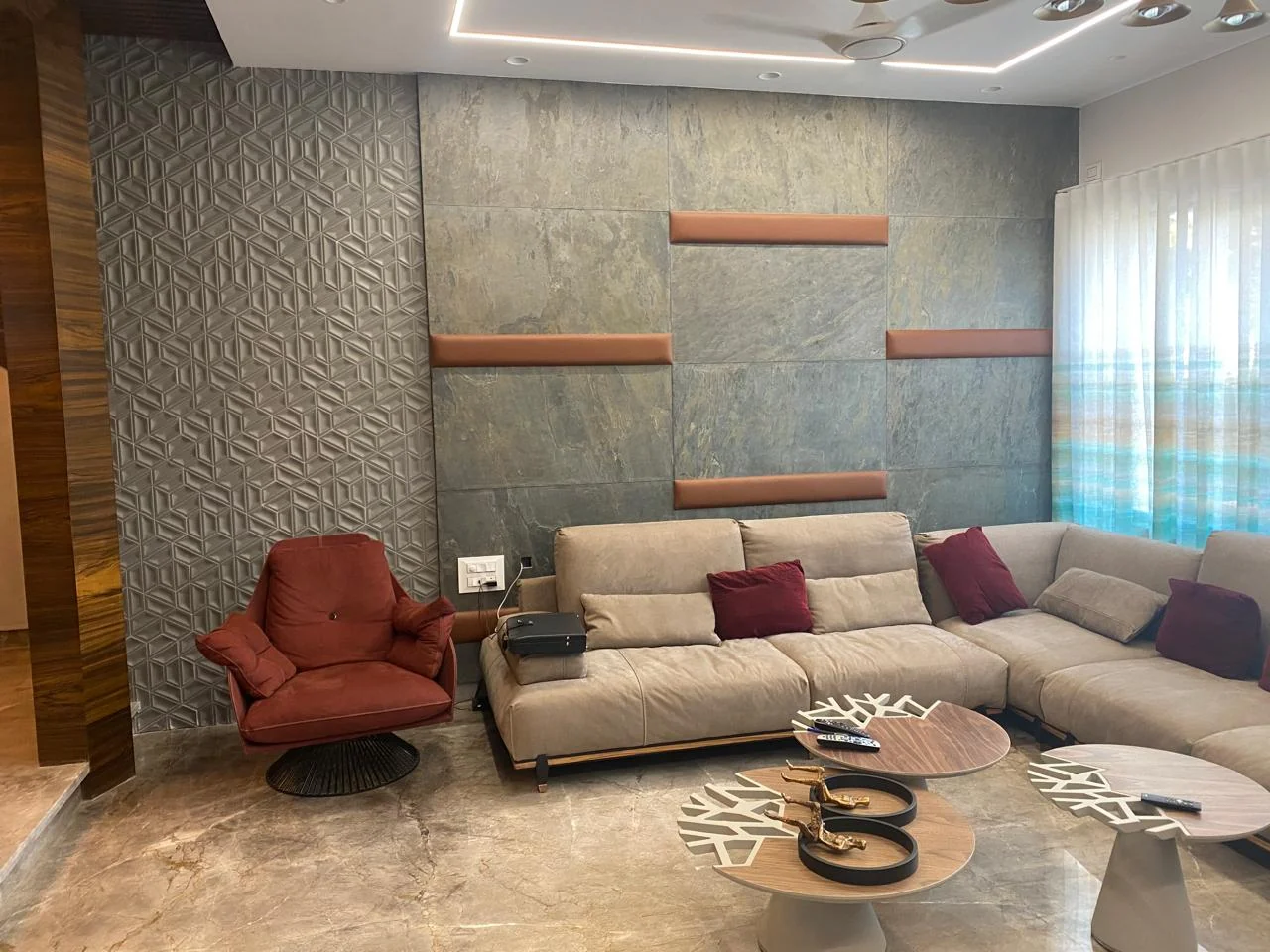 Completed living room with a textured white feature wall, floating timber shelves, a large beige sectional sofa and polished marble flooring