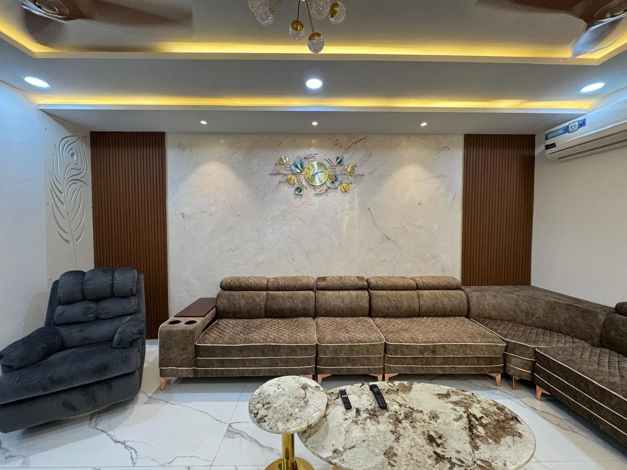 Completed living room with vertical timber batten panelling, a marble feature wall with an inlaid medallion and a deep sectional sofa