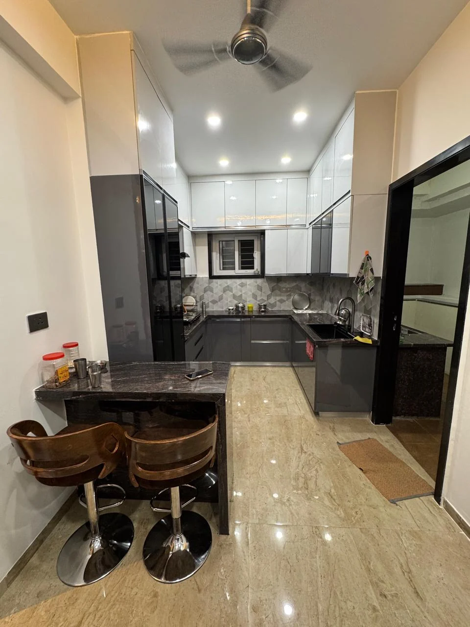 U-shaped modular kitchen in grey gloss with a granite counter carried into a breakfast bar