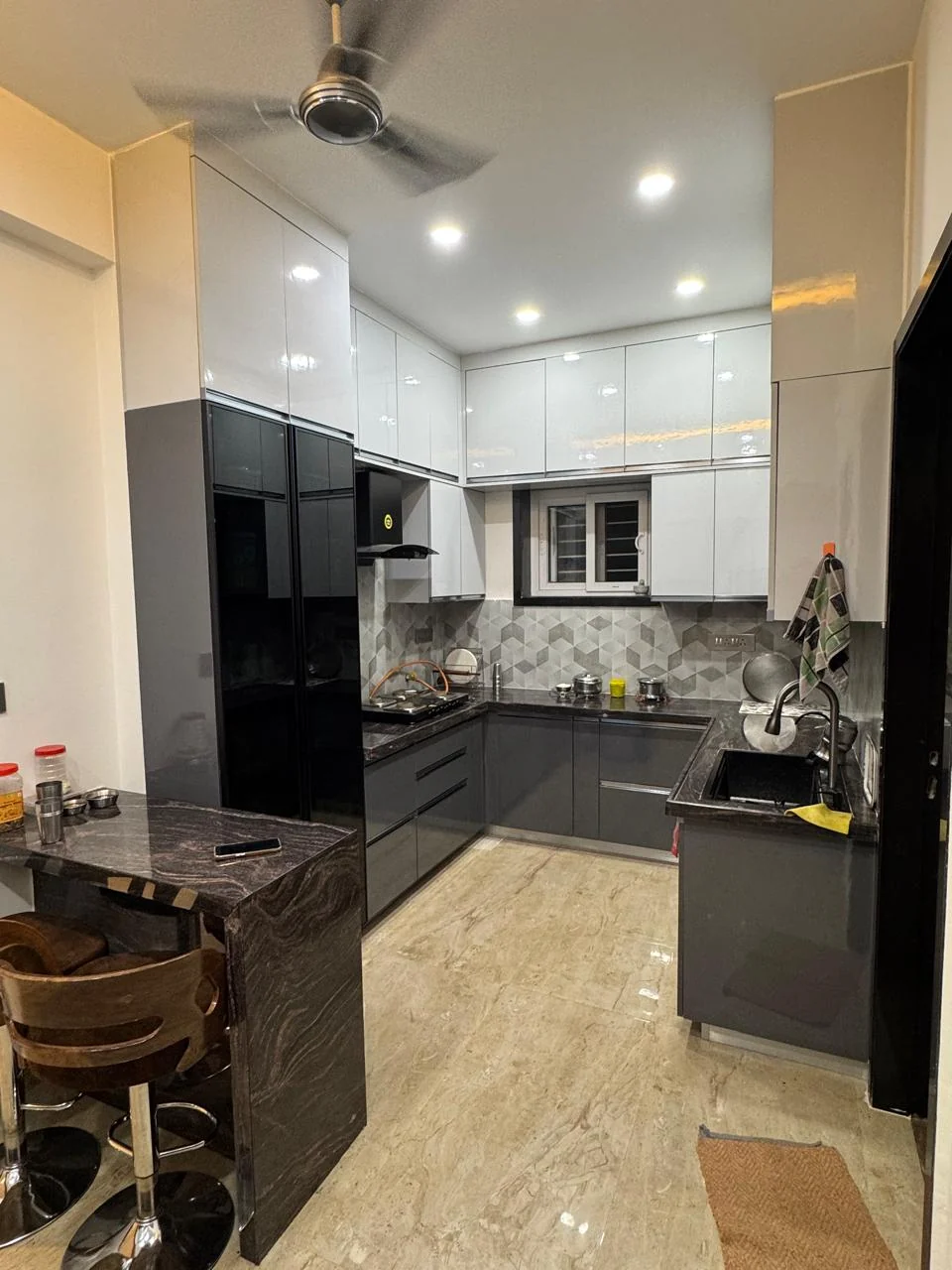 Modular kitchen with a hexagonal tile backsplash and a dark granite counter