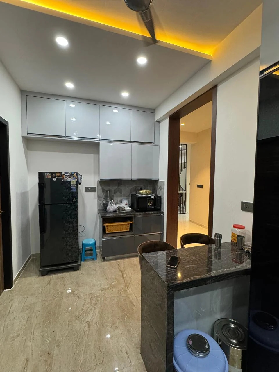 Modular kitchen with a tall storage and appliance run beside a granite breakfast counter