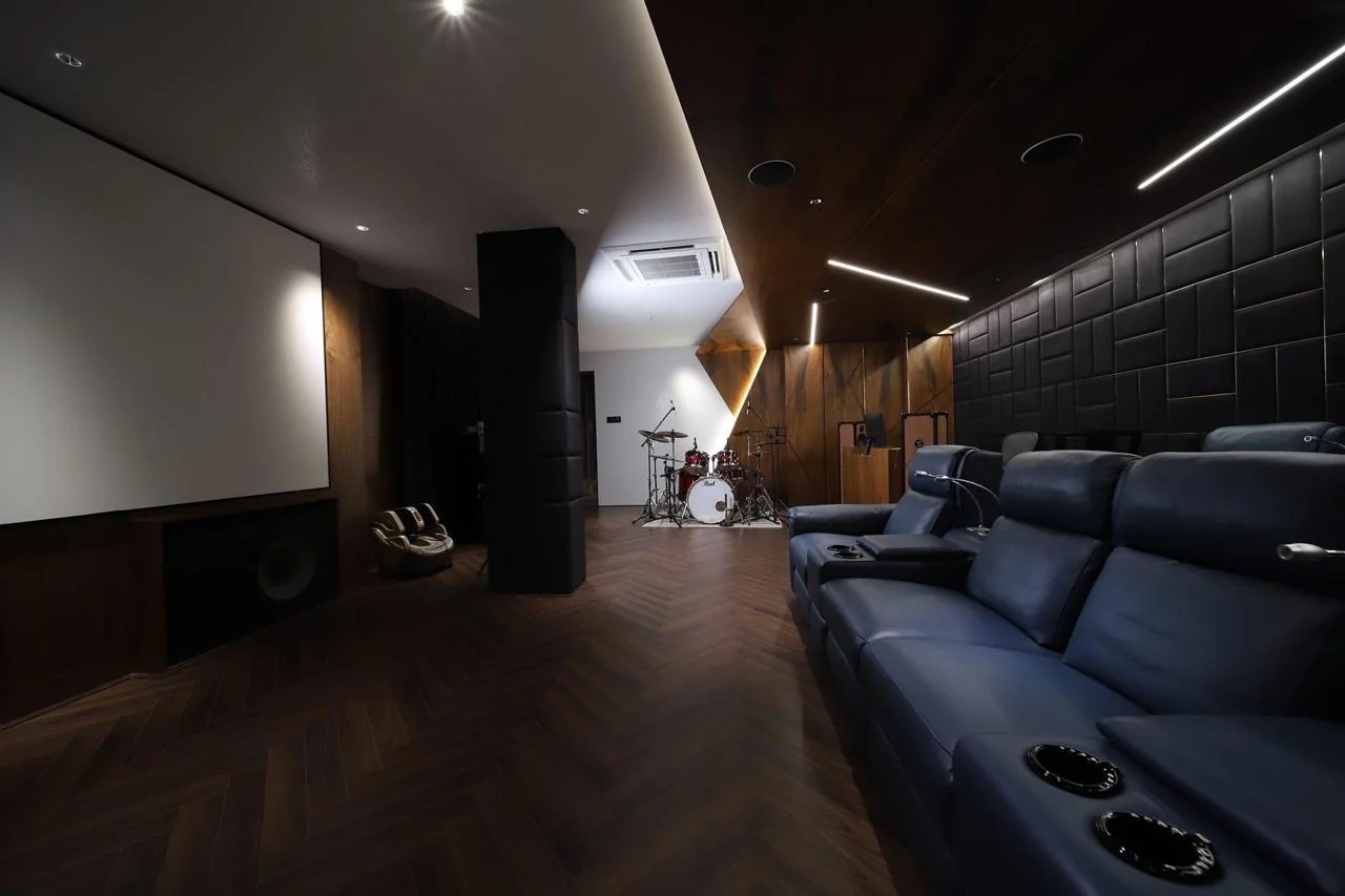 Music room with deep acoustic wall panelling, lounge seating and a projection screen