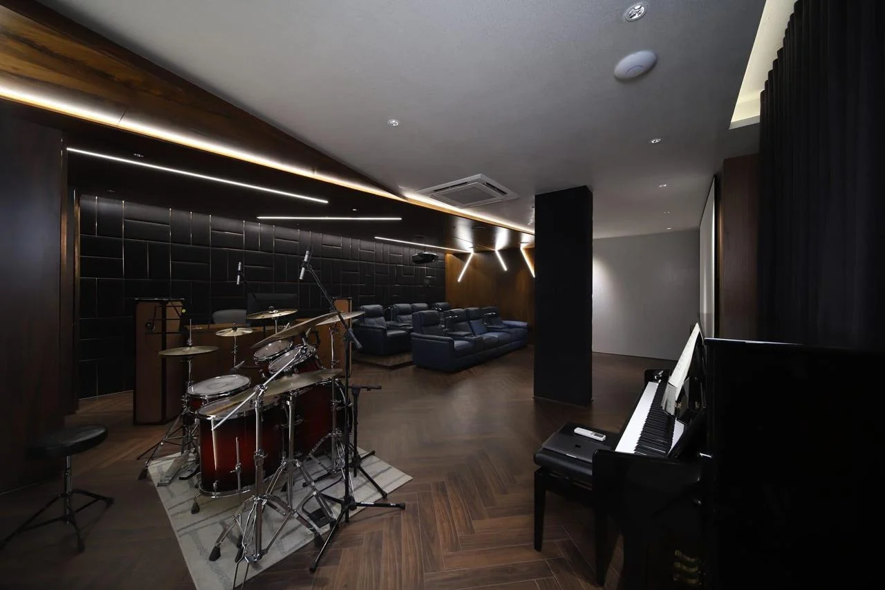 Music room with a grand piano and drum kit on a herringbone timber floor