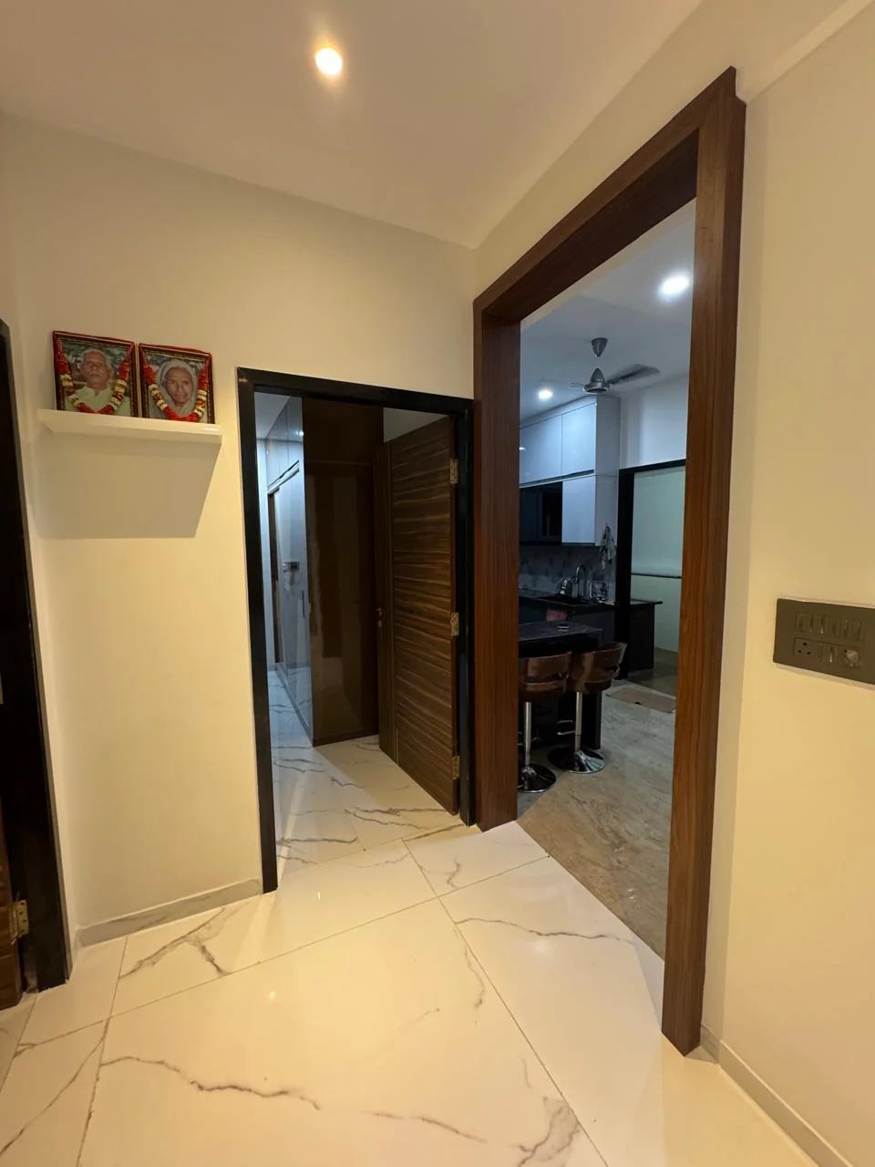 Passage with framed artwork and timber doors, the kitchen visible beyond