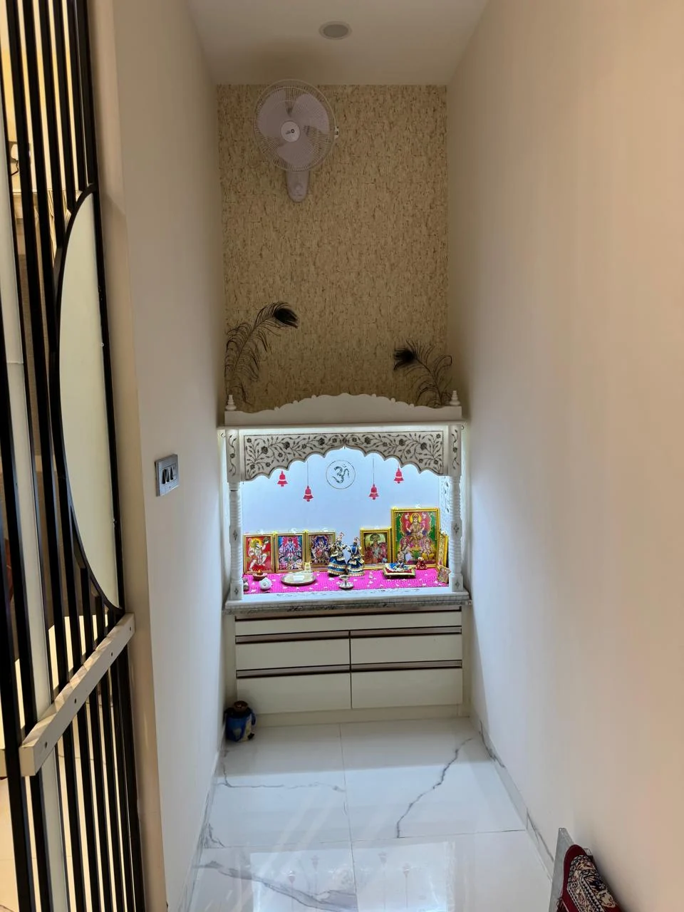 Wide view of the pooja room showing the carved marble mandir arch in its wall