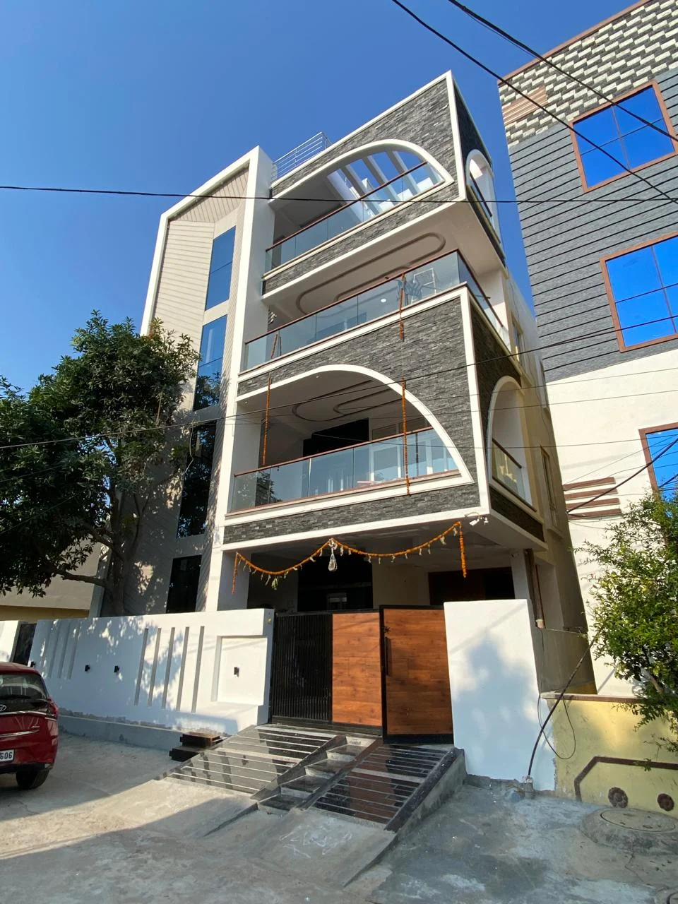 The same residence façade in daylight, showing split-face stone cladding within white rendered arched frames