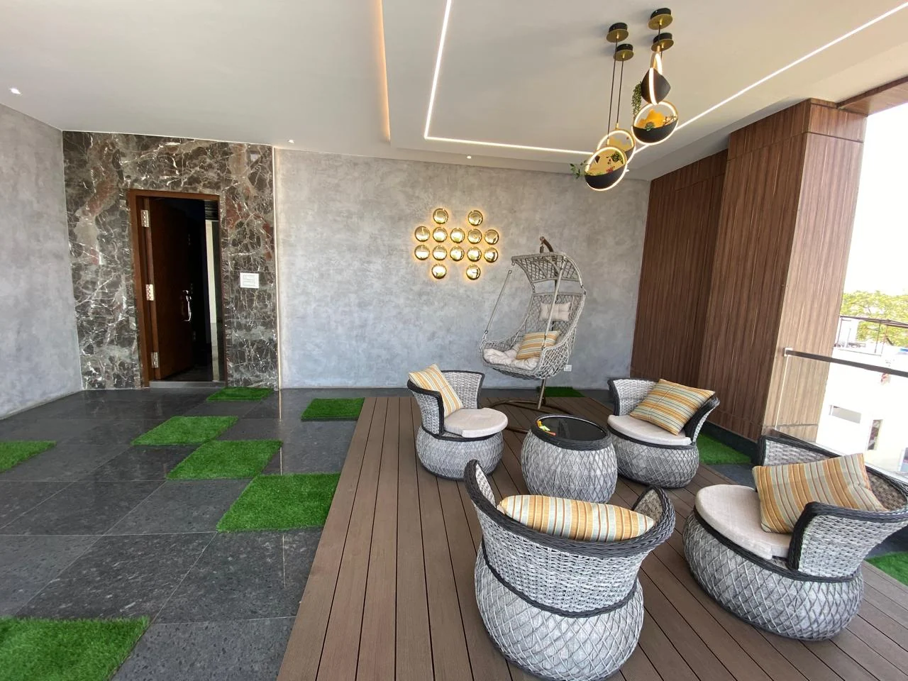 Timber terrace deck with rattan swing chairs beneath pendant lighting