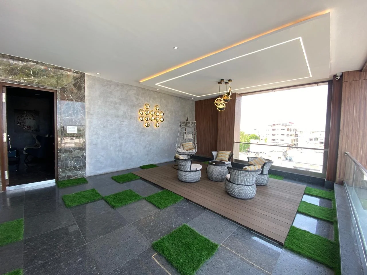 Terrace lounge with a checkerboard of stone slabs and planted grass and rattan seating