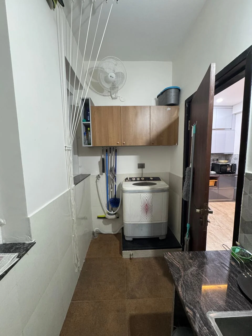 Utility area with a washing machine beneath overhead storage