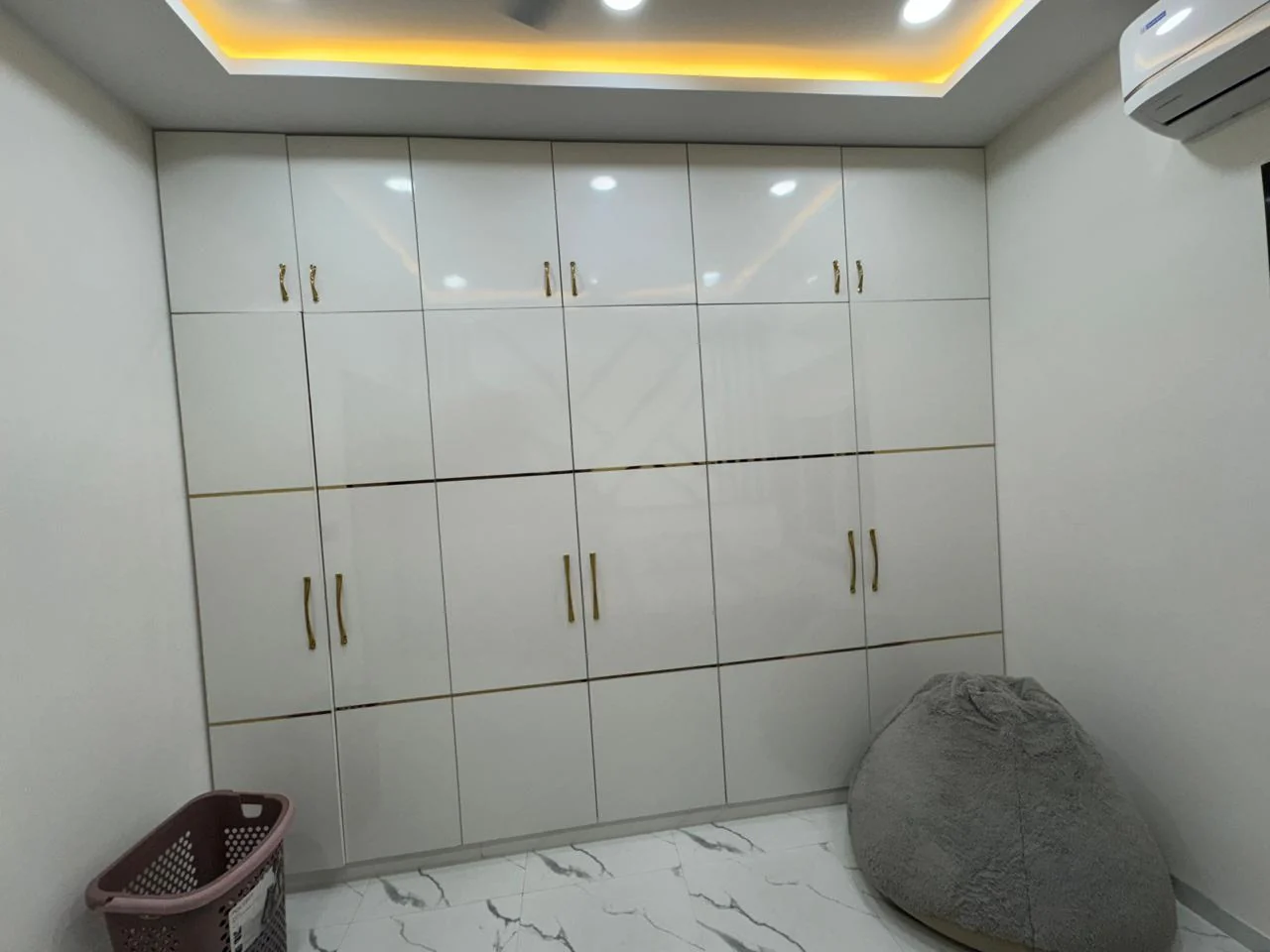 Full wall of white gloss wardrobe shutters with fine brass inlay lines